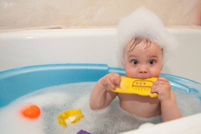 소년은 물 온도계가 달린 욕조에서 목욕을합니다.