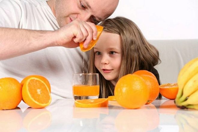 संतरे का रस एक बच्चे के साथ पिताजी बनाते हैं